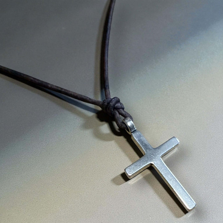 Handcrafted solid sterling silver cross on an adjustable leather cord. Unisex. Available in black, dark brown, or red brown. Made in USA