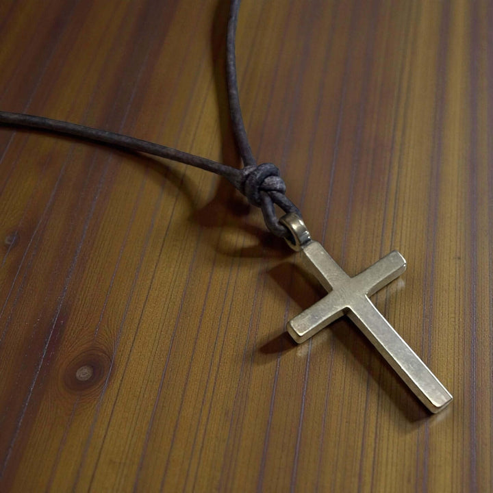 Handcrafted solid bronze cross on an adjustable leather cord. Unisex, red brown or dark brown. Made in USA with a lifetime warranty