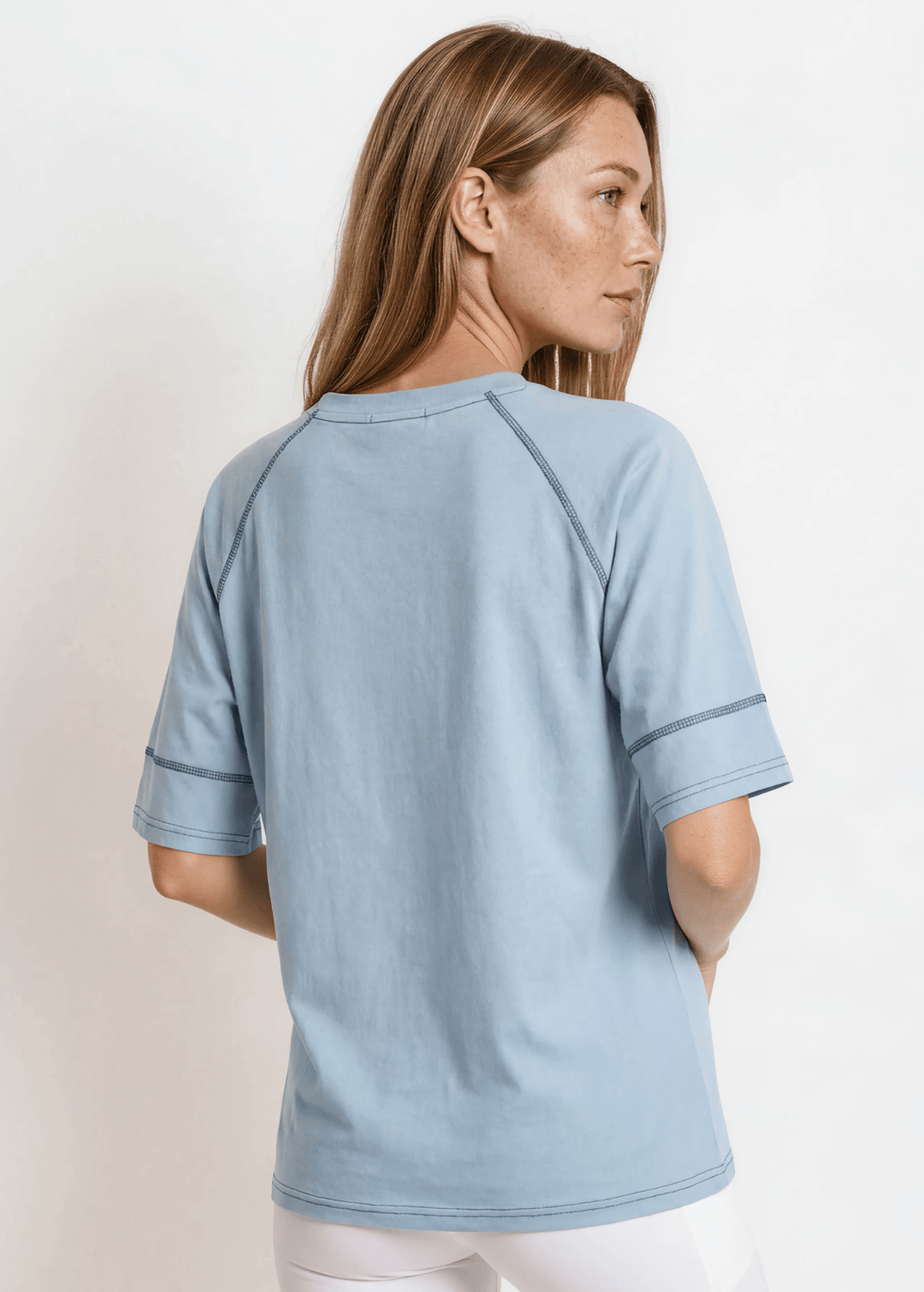 Evelyn Exposed Stitch Tee in Denim Blue. Oversized boxy fit, 3/4 raglan sleeves, contrast topstitching, super soft. Made in USA. Sizes S–XL.