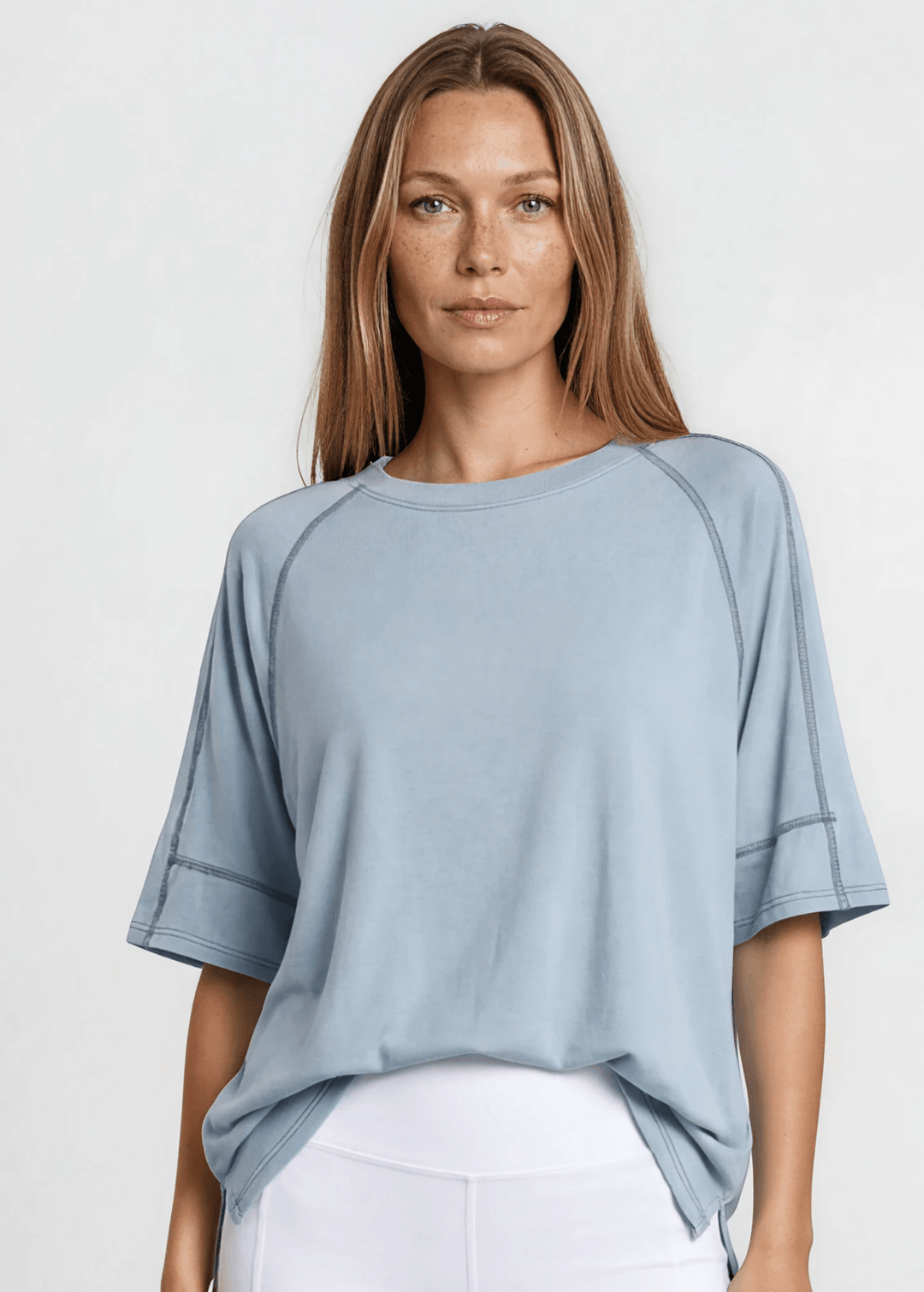  Evelyn Exposed Stitch Tee in Denim Blue. Oversized boxy fit, 3/4 raglan sleeves, contrast topstitching, super soft. Made in USA. Sizes S–XL.