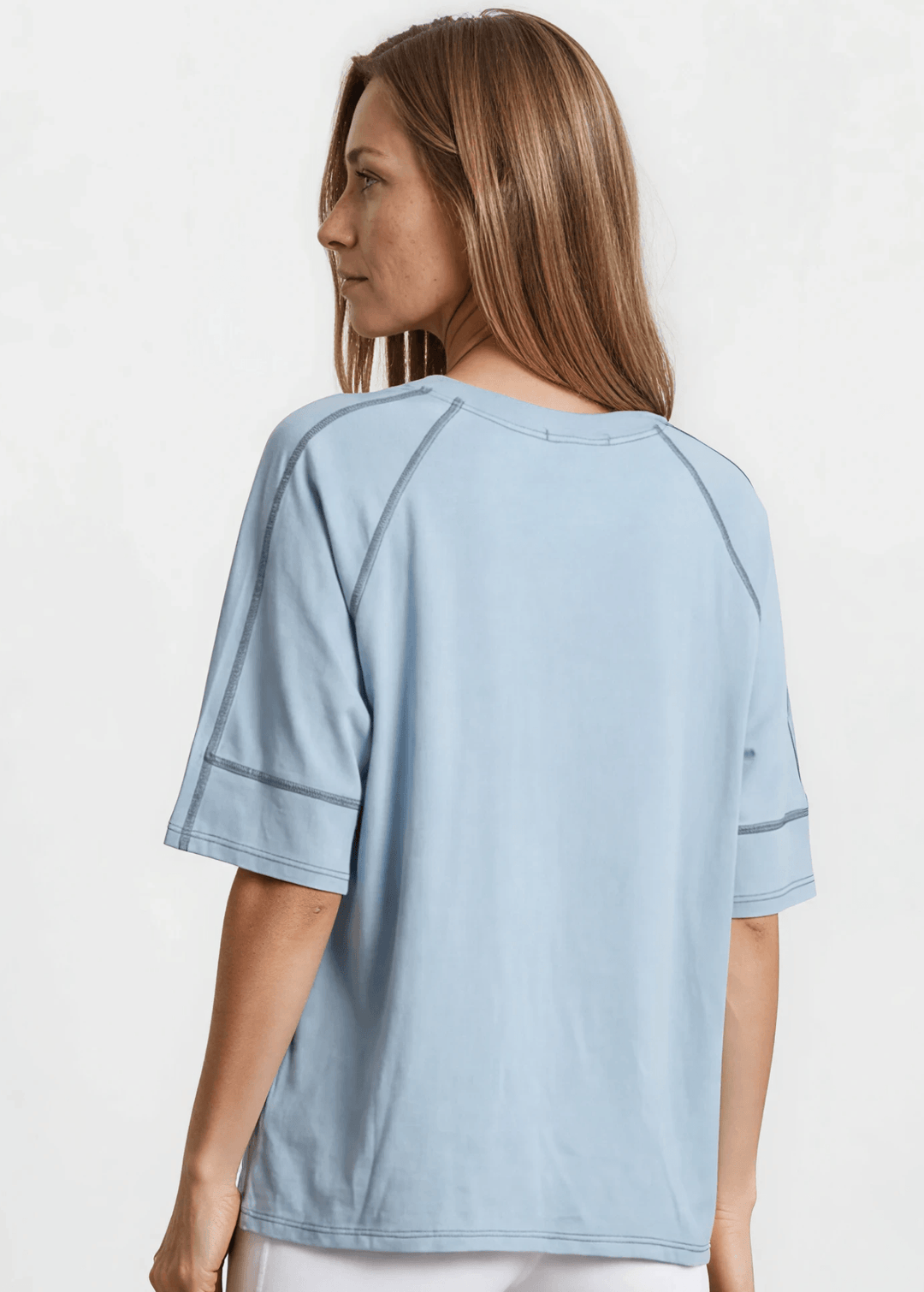  Evelyn Exposed Stitch Tee in Denim Blue. Oversized boxy fit, 3/4 raglan sleeves, contrast topstitching, super soft. Made in USA. Sizes S–XL.