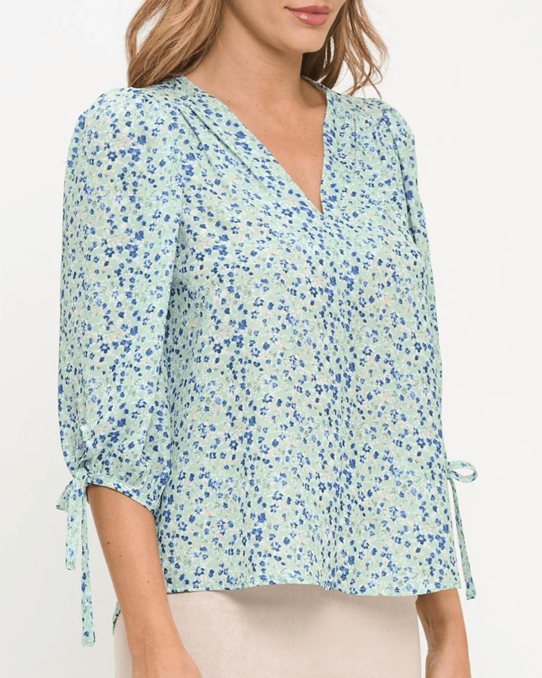 Delilah Ditsy Floral Top in Sage. V-neck, 3/4 tie sleeves, relaxed fit, 100% polyester. Feminine floral blouse made in the USA. Sizes S–L.