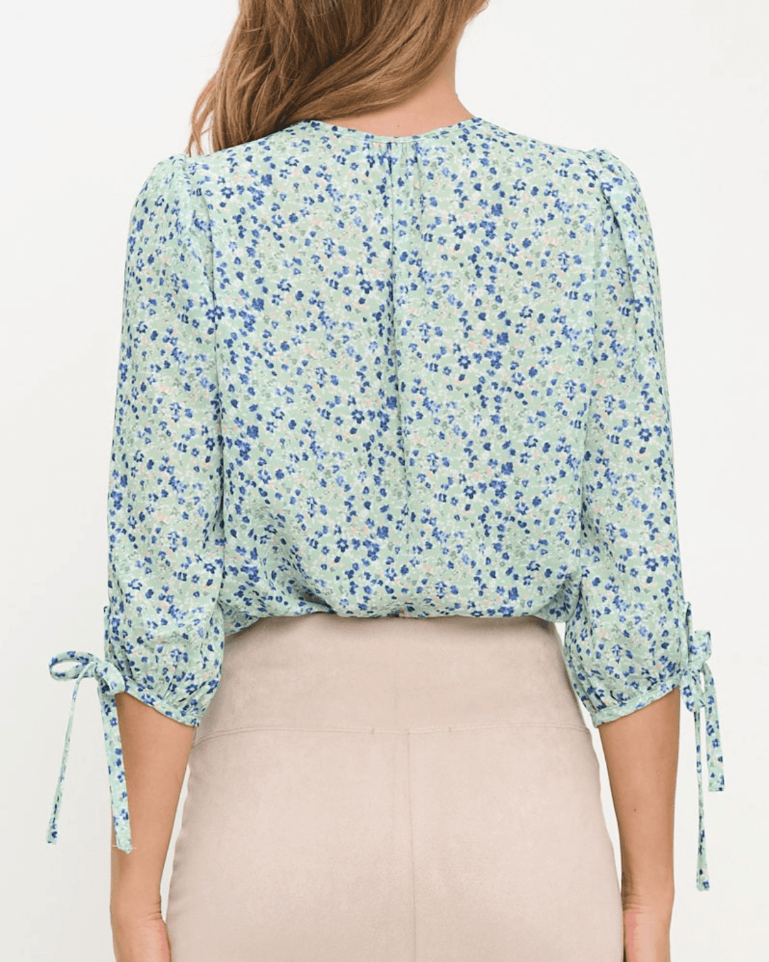 Delilah Ditsy Floral Top in Sage. V-neck, 3/4 tie sleeves, relaxed fit, 100% polyester. Feminine floral blouse made in the USA. Sizes S–L.