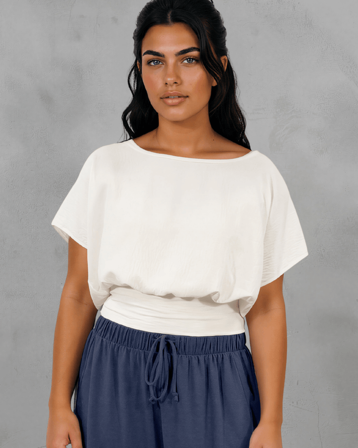Shop the Sandra Flowy Short Sleeve Top with Smocked Waist in White. Blousy crop top, fitted smocked waist, 100% polyester. Made in USA. Sizes S–L.