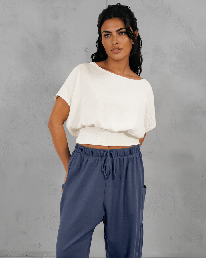 Shop the Sandra Flowy Short Sleeve Top with Smocked Waist in White. Blousy crop top, fitted smocked waist, 100% polyester. Made in USA. Sizes S–L.
