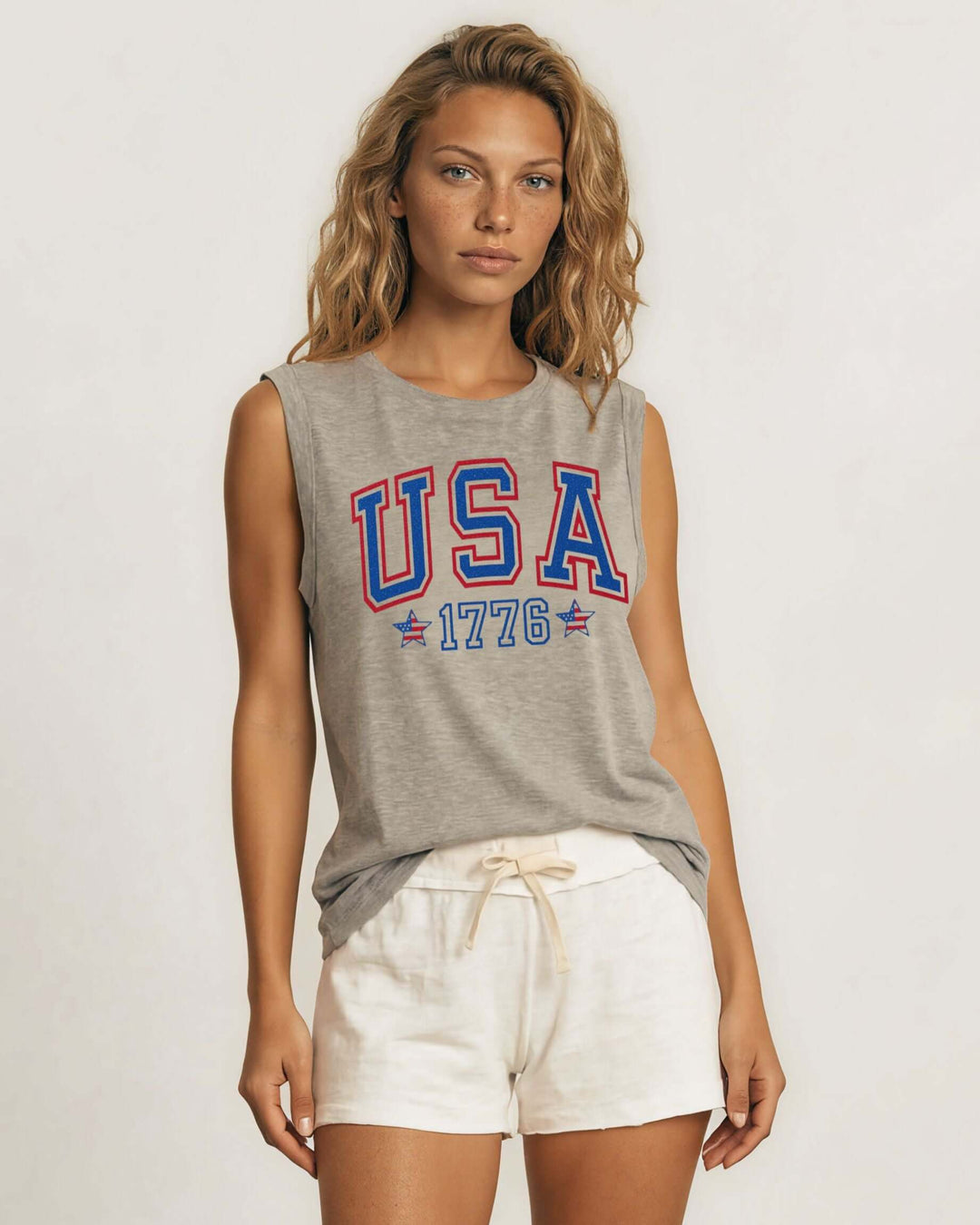 Glitter USA varsity graphic muscle tee with 1776 &amp; flag star accents. Made in USA, relaxed fit, 75% cotton. Perfect for 4th of July. Sizes S-L.