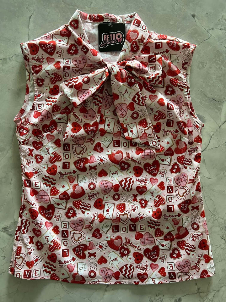 Vintage Tops This top is for the vintage lover at heart! Shown in our XOXO print, this 100% cotton top features bust darts for a flattering silhouette, a side zippered closure for ease of wear, and an oversized bow at the neckline for that perfect 1950&