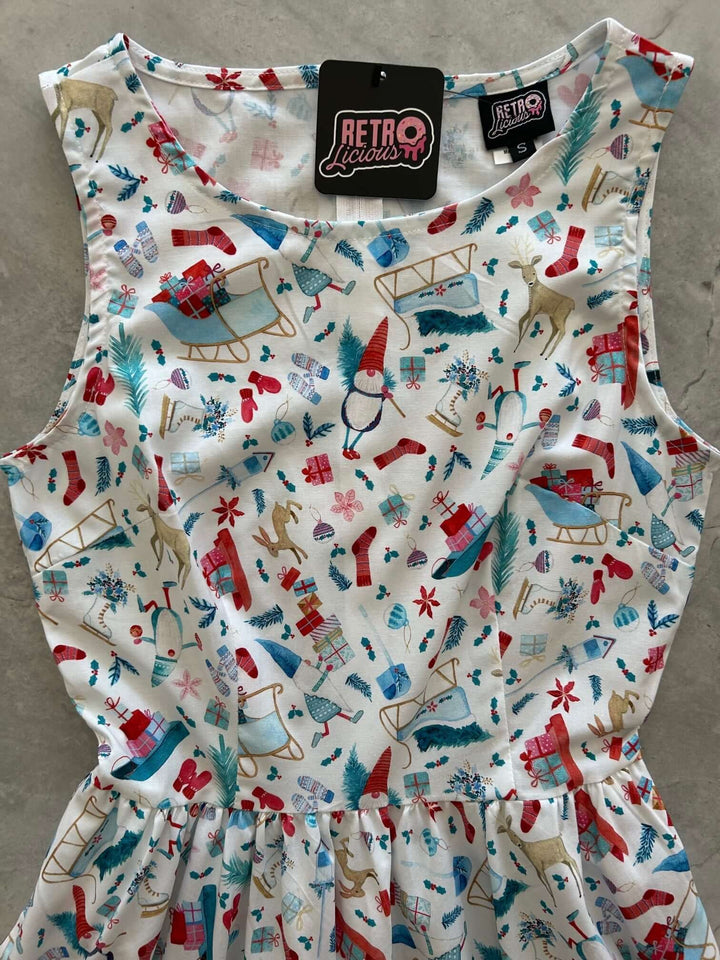 Introducing our Winter Cheer Vintage Dress. This dress boasts a fun and playful print featuring gnomes, sleds, ice skates, mittens, and reindeer. It&