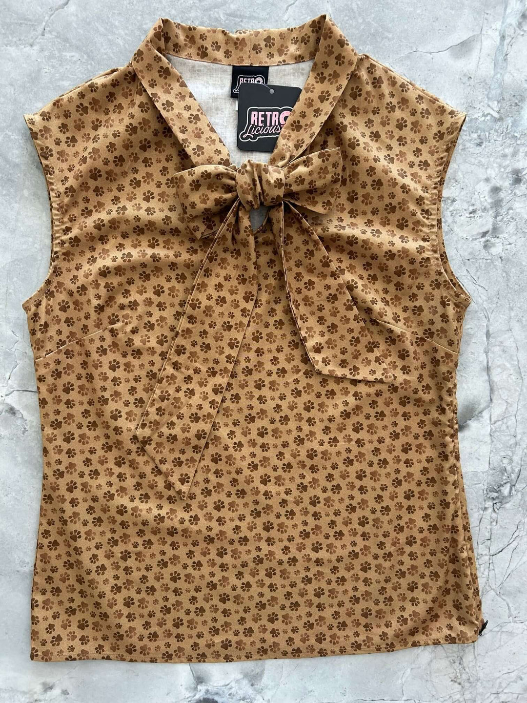 Vintage Style Tops This top is for the vintage lover at heart! Now available in our Paw print. This 100% cotton top features bust darts for a flattering silhouette, a side zippered closure for ease of wear, and an oversized bow at the neckline for that perfect 1950&
