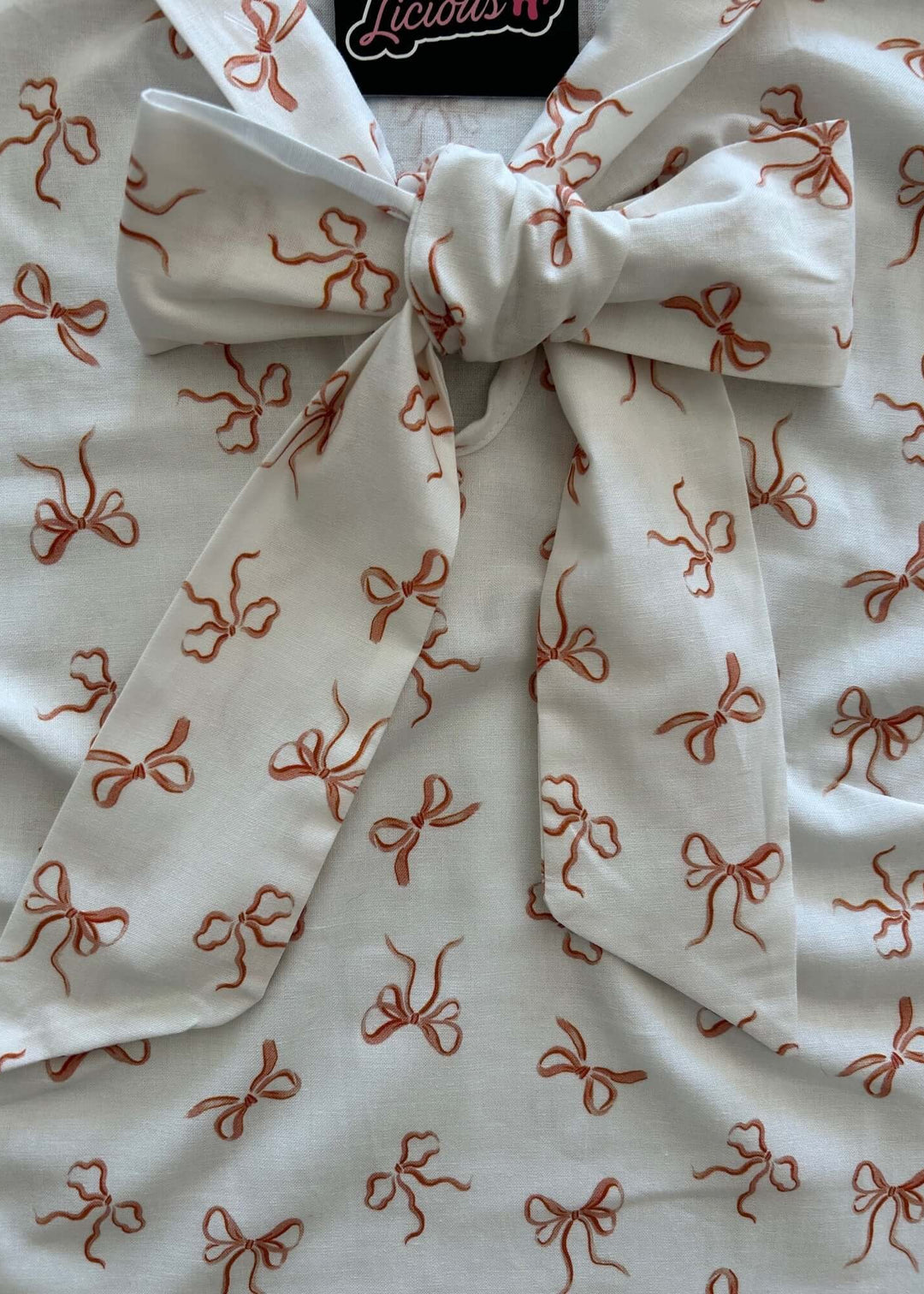 Vintage Style Tops This top is for the vintage lover at heart! Now available in our Pink Bows print. This 100% cotton top features bust darts for a flattering silhouette, a side zippered closure for ease of wear, and an oversized bow at the neckline for that perfect 1950&