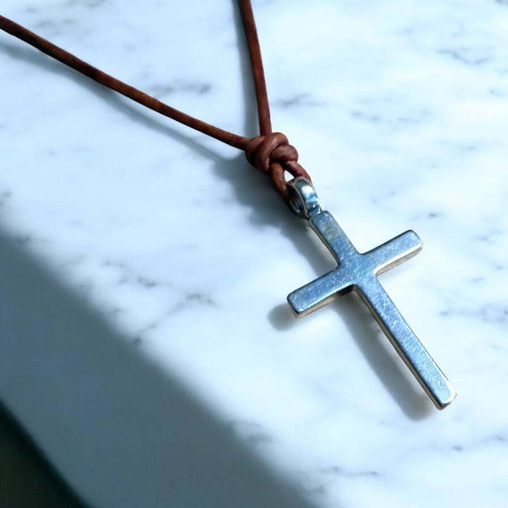 Handcrafted solid sterling silver cross on an adjustable leather cord. Unisex. Available in black, dark brown, or red brown. Made in USA