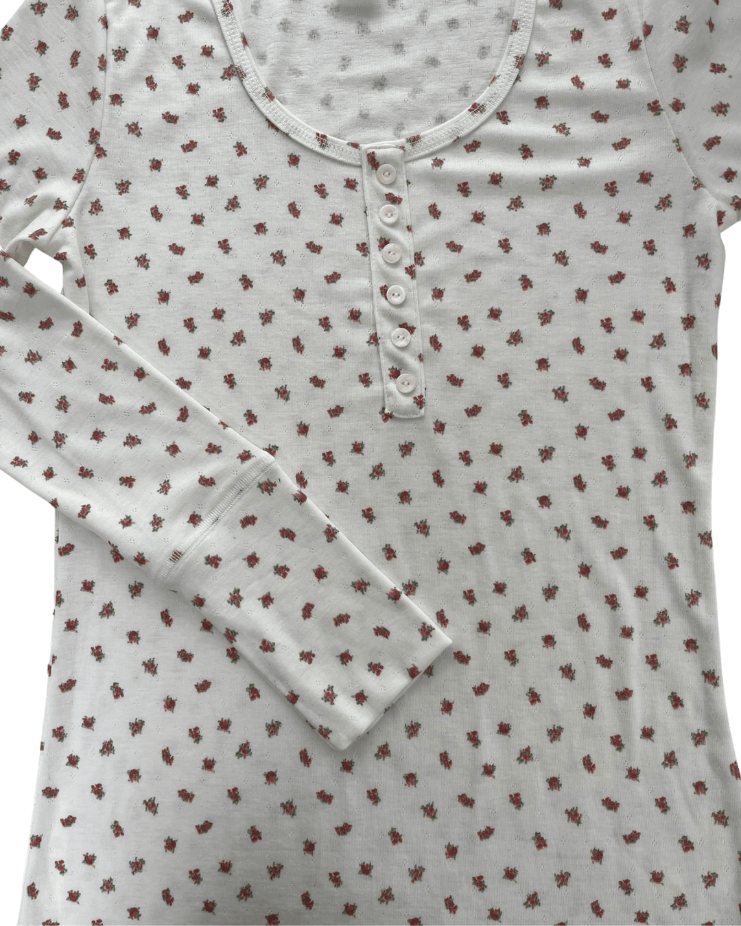 Made in USA. Ivory and red ditsy floral fitted Henley top. Scoop neck, button placket, long sleeves, stretchy knit. 95% polyester. Sizes S–XL.