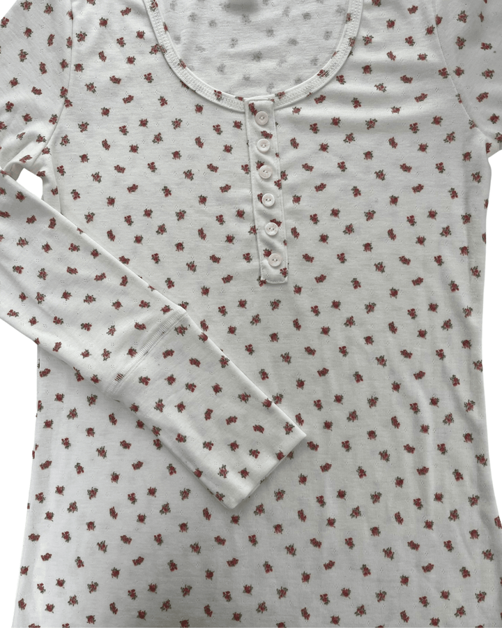 Made in USA. Ivory and red ditsy floral fitted Henley top. Scoop neck, button placket, long sleeves, stretchy knit. 95% polyester. Sizes S–XL.