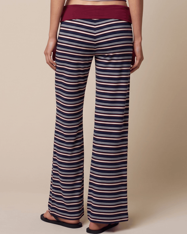 A woman wearing Made in USA striped pajama set with a fitted tank, fold-over waistband, and relaxed wide-leg pants in burgundy, navy, and white. Super soft and stretchy fabric.