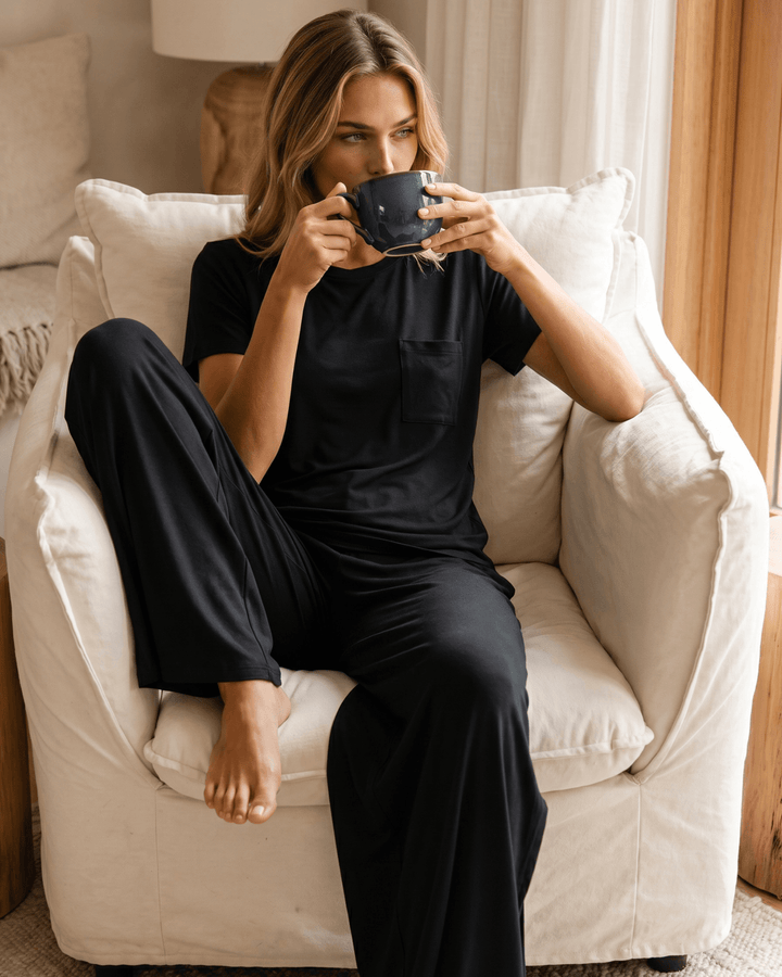 "Black two-piece loungewear set featuring a relaxed-fit short-sleeve crew neck tee with a chest pocket and wide-leg pants with split hems and an elastic waistband, in a soft stretch fabric blend. Made in USA."