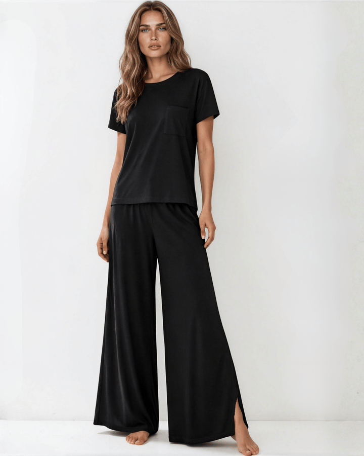 "Black two-piece loungewear set featuring a relaxed-fit short-sleeve crew neck tee with a chest pocket and wide-leg pants with split hems and an elastic waistband, in a soft stretch fabric blend. Made in USA."