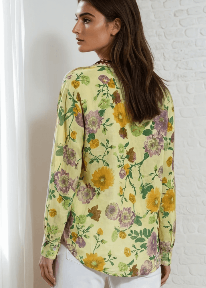 Bask in the beauty of effortless bohemian charm with the Carla Top. Crafted from soft, breathable cotton voile, this piece features a vibrant floral print in sun-kissed tones of golden marigold, lilac, and fresh green. The hand-embroidered deep red bib adds an artisanal touch, making each blouse unique. Designed with a relaxed silhouette and a flattering V-neckline, it&