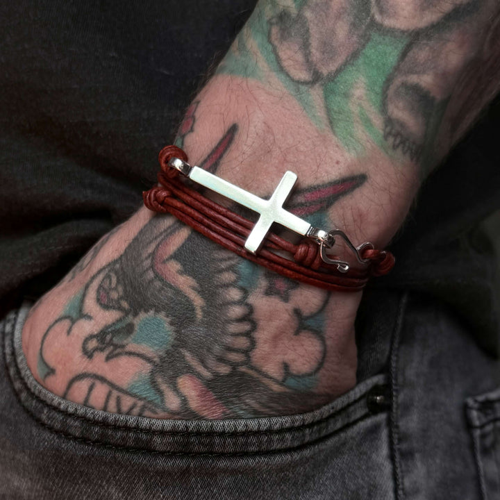 Handcrafted solid sterling silver cross bracelet on a triple-wrap leather cord. One size fits all. Made in USA with a lifetime warranty.