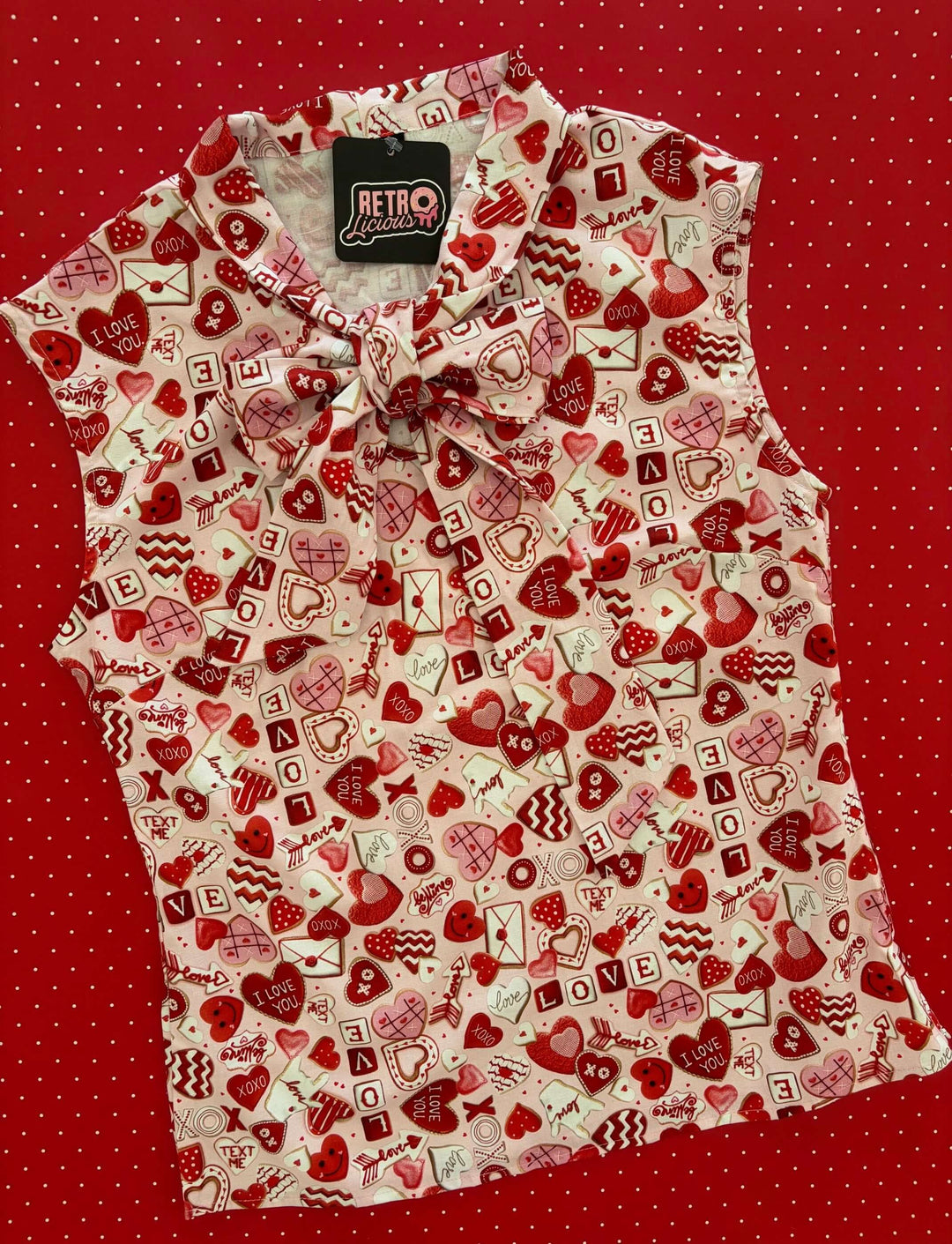 Vintage Tops This top is for the vintage lover at heart! Shown in our XOXO print, this 100% cotton top features bust darts for a flattering silhouette, a side zippered closure for ease of wear, and an oversized bow at the neckline for that perfect 1950&