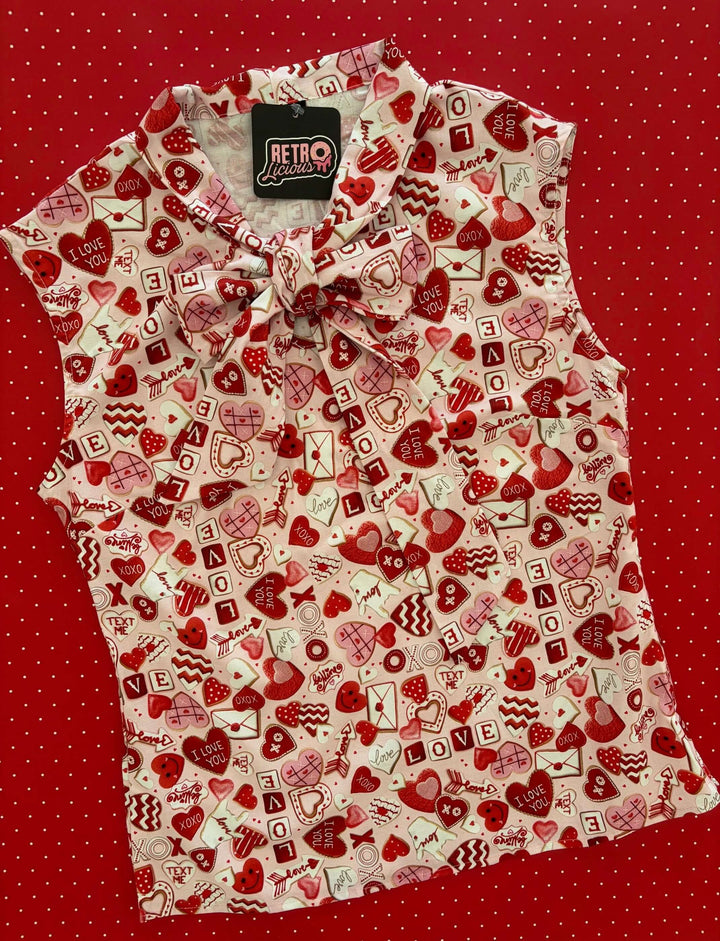 Vintage Tops This top is for the vintage lover at heart! Shown in our XOXO print, this 100% cotton top features bust darts for a flattering silhouette, a side zippered closure for ease of wear, and an oversized bow at the neckline for that perfect 1950&