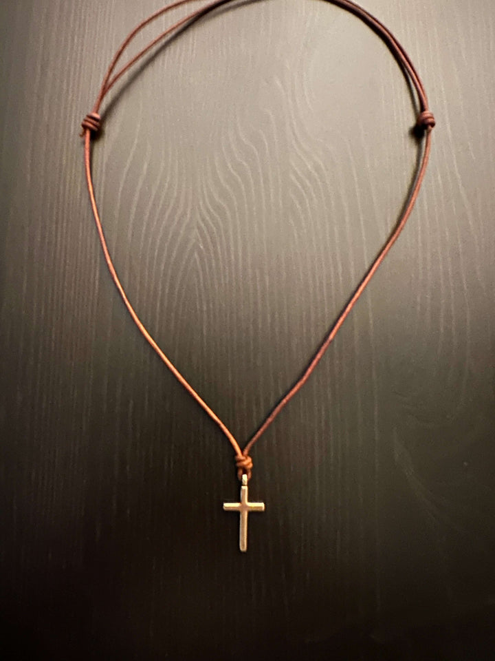 Handcrafted solid bronze cross on an adjustable leather cord. Unisex, red brown or dark brown. Made in USA with a lifetime warranty