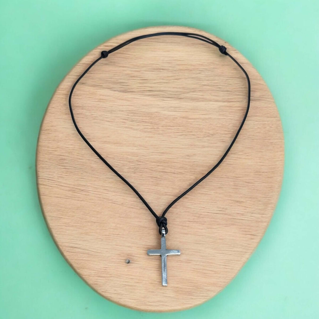 Handcrafted solid sterling silver cross on an adjustable leather cord. Unisex. Available in black, dark brown, or red brown. Made in USA