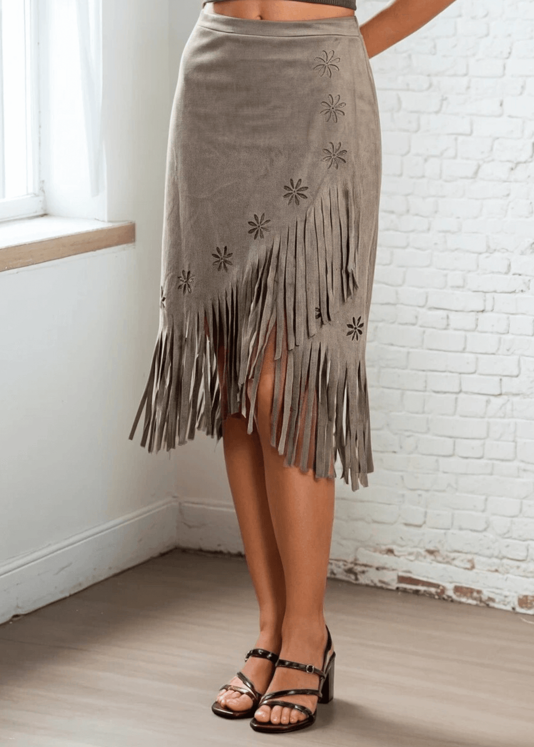 Add a unique piece to your wardrobe with the Leia Laser Cut Fringe Overlay Suede Skirt, a statement piece crafted right here in the USA. This skirt features an intricate laser-cut floral pattern with delicate fringe detailing and a chic wrap overlay silhouette that flatters every figure. 